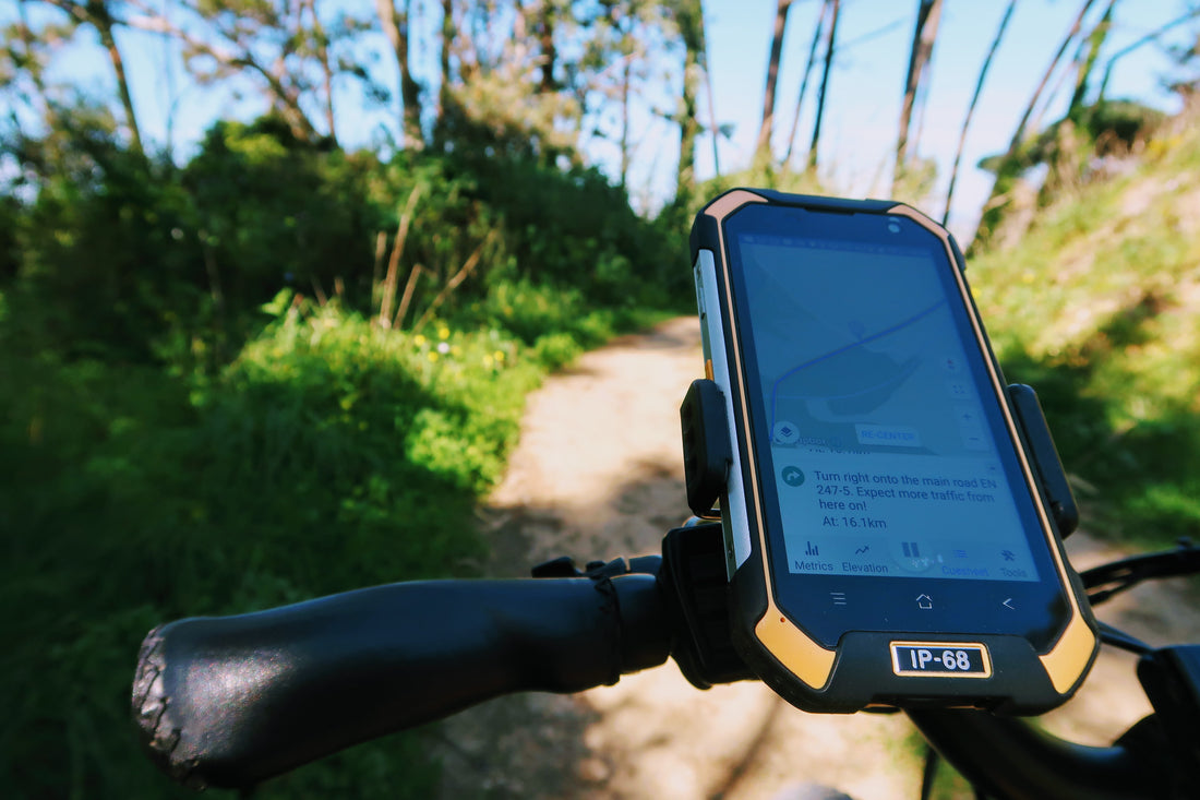 Smartphone on a handlebar phone holder on a bicycle on a forest trail